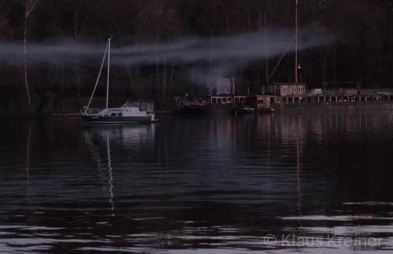 Anfang März 2023 in Berlin: Einige Hausboote schaukeln am Abend in der Rummelsburger Bucht durch leichte Rauchschwaden.