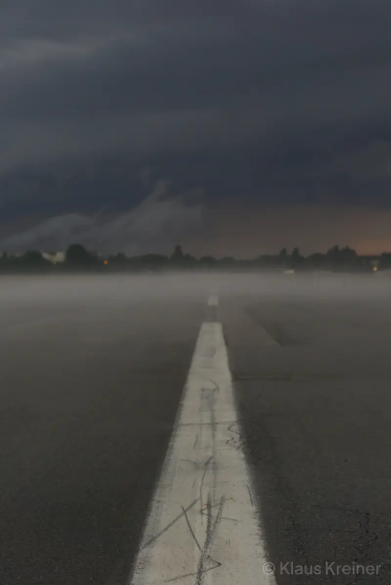 Anfang August 2021 in Berlin: Ein Nebel über der Rollbahn mit scharfem Mittelstreifen kündigt auf dem Tempelhofer Feld ein Unwetter an.