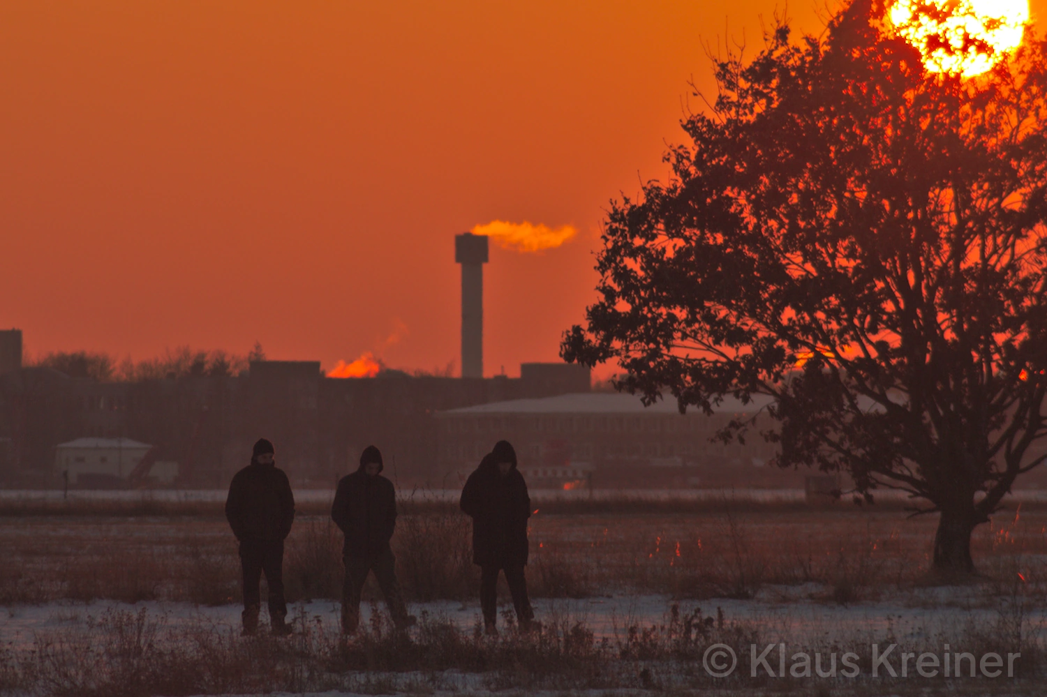 Anfang Januar 2017 in Berlin: Drei Menschen flanieren an einem Wintertag im Abendrot, rechts sehen wir die untergehende Sonne.