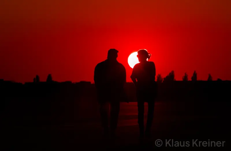 Anfang Oktober 2018 in Berlin: Ein Pärchen flaniert im Abendrot auf der Rollbahn vom Tempelhofer Feld der untergehenden Sonne entgegen.