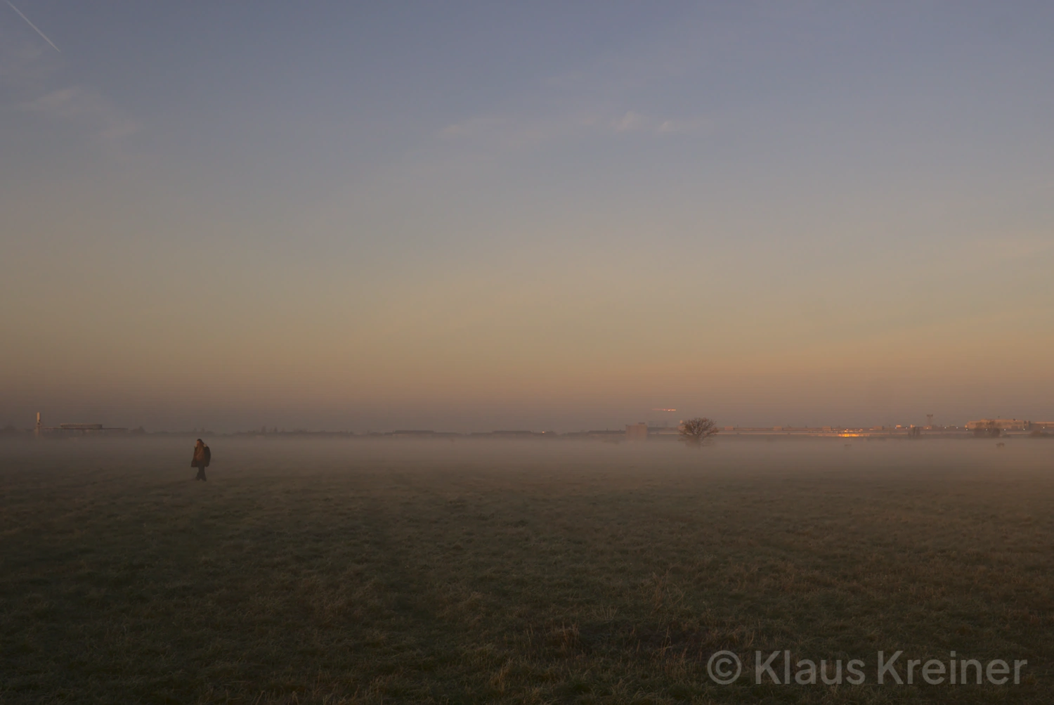 Mitte November 2021 in Berlin: An einem frühen nebligen Morgen geht eine Person über die große Fläche vom Tempelhofer Feld.