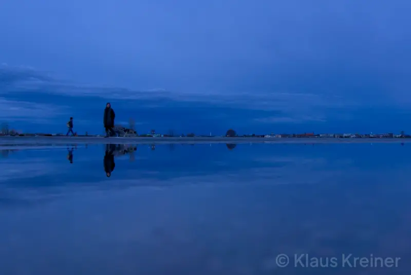 Anfang März 2019 in Berlin: Eine Person befindet sich während der blauen Stunde im Spiegelbild einer Wasserfläche.