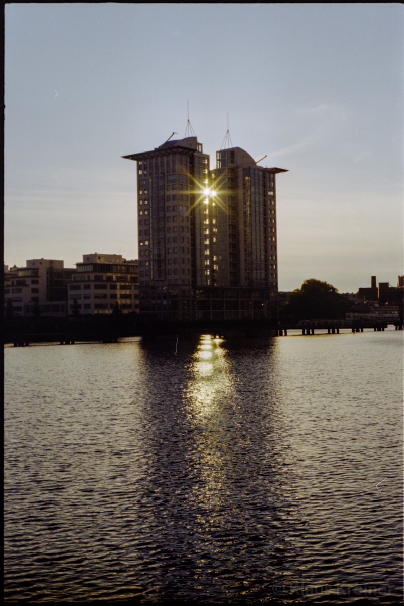 Ein Hochhaus an der Spree reflektiert die Sonne auf das Wasser.